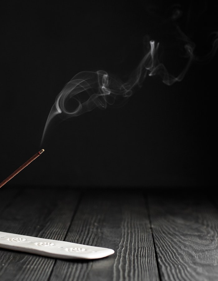 A single incense stick burning on a ceramic holder