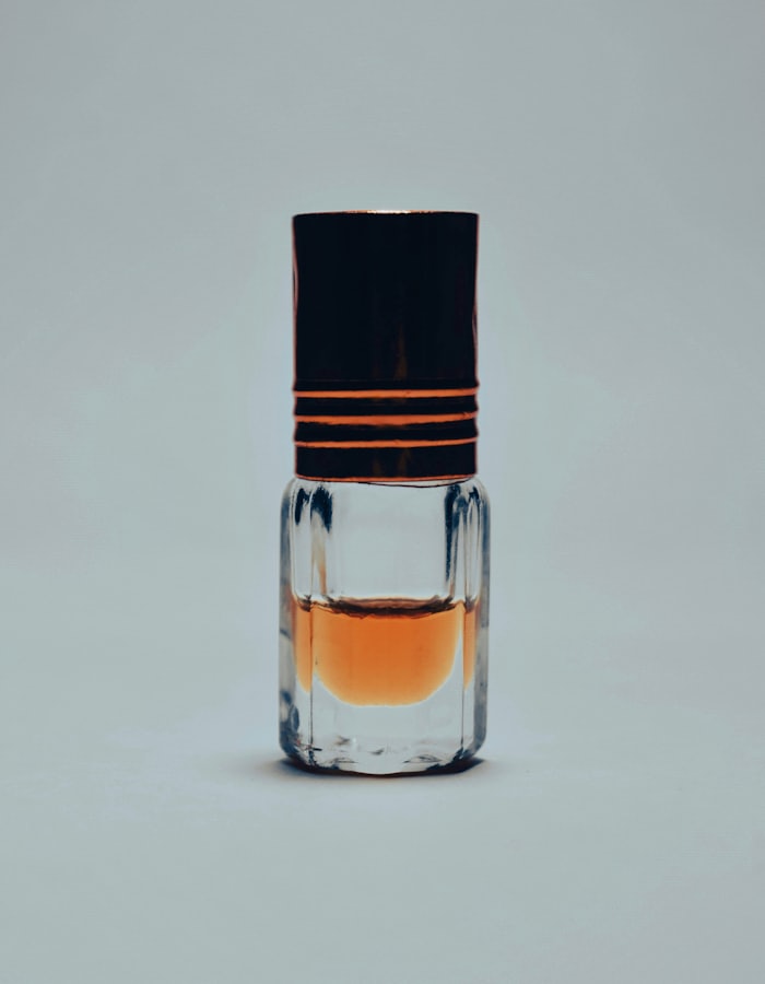 A small glass attar bottle holding amber perfume oil